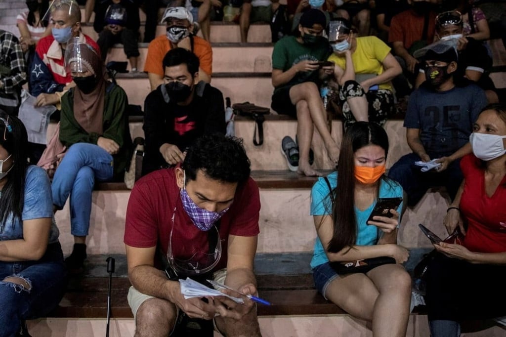 Filipinos use their smartphones as they queue up to receive a Covid-19 vaccine shot in Manila. Photo: Reuters Filipinos use their smartphones as they queue up to receive a Covid-19 vaccine shot in Manila. Photo: Reuters