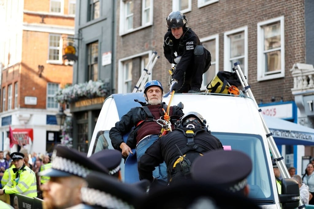 Police officers try to remove a demonstrator who glued himself to the top of a van during an Extinction Rebellion protest in London on Monday. Photo: Reuters