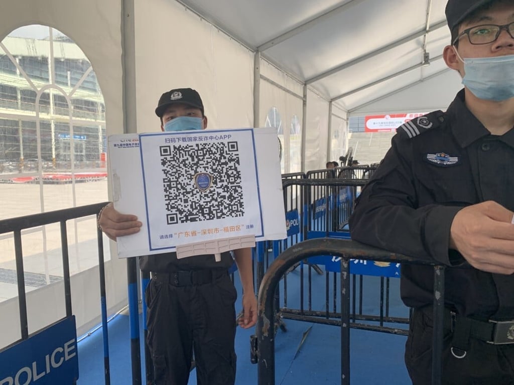 A security guard presents the QR code 'National Anti-fraud Centre' app at the entrance of Shenzhen Convention and Exhibition Center on April 12, 2021. Photo: Yujie Xue A security guard presents the QR code 'National Anti-fraud Centre' app at the entrance of Shenzhen Convention and Exhibition Center on April 12, 2021. Photo: Yujie Xue
