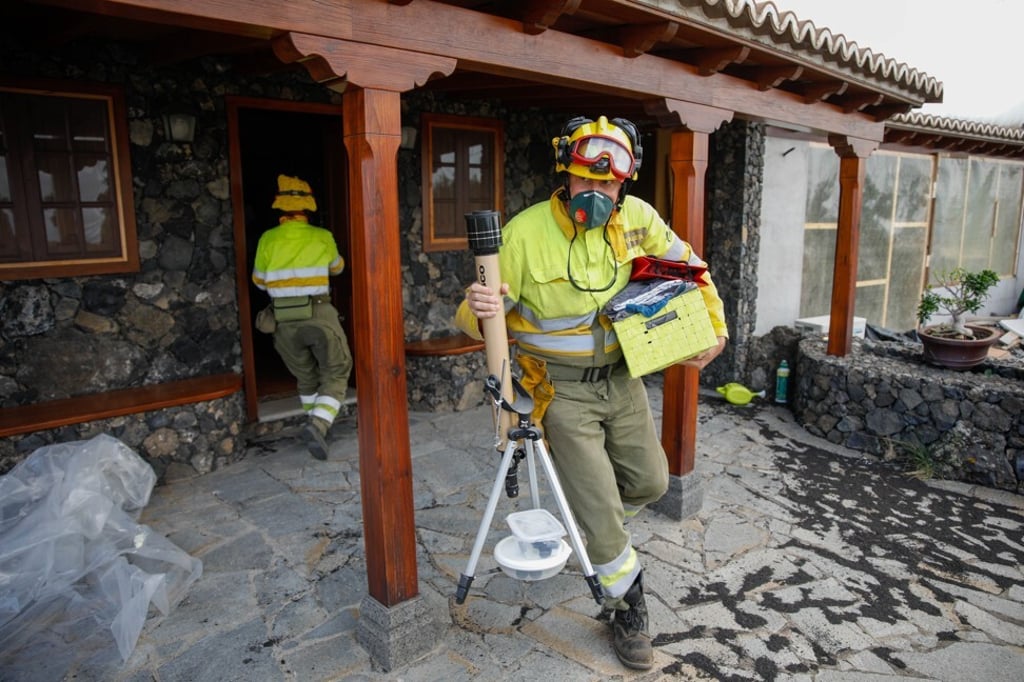 A firefighter help residents to evacuate as lava from a volcanic eruption approaches. Photo: dpa
