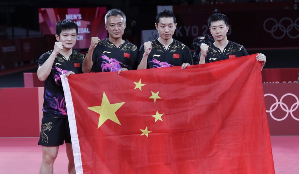 China’s Tokyo 2020 men’s team gold medallists Ma Long, Xu Xin and Fan Zhendong are joined by head coach Qin Zhijian after beating Germany in the final. Photo: EPA China’s Tokyo 2020 men’s team gold medallists Ma Long, Xu Xin and Fan Zhendong are joined by head coach Qin Zhijian after beating Germany in the final. Photo: EPA