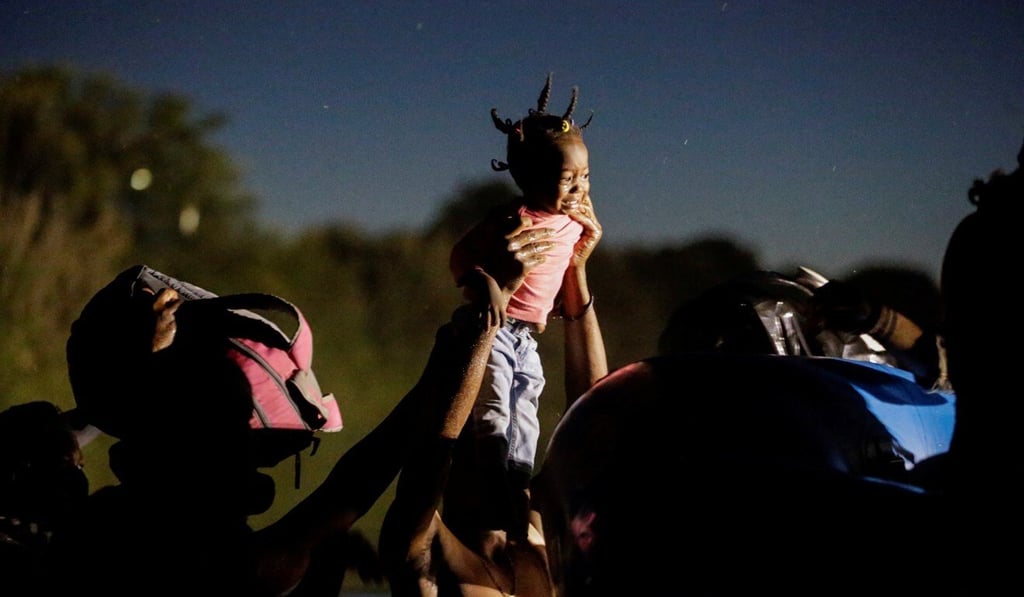 Migrants crossing the Rio Grande to seek refuge in the US hold up a girl to be helped by Border Patrol agents on an inflatable boat on Thursday. Photo: Reuters