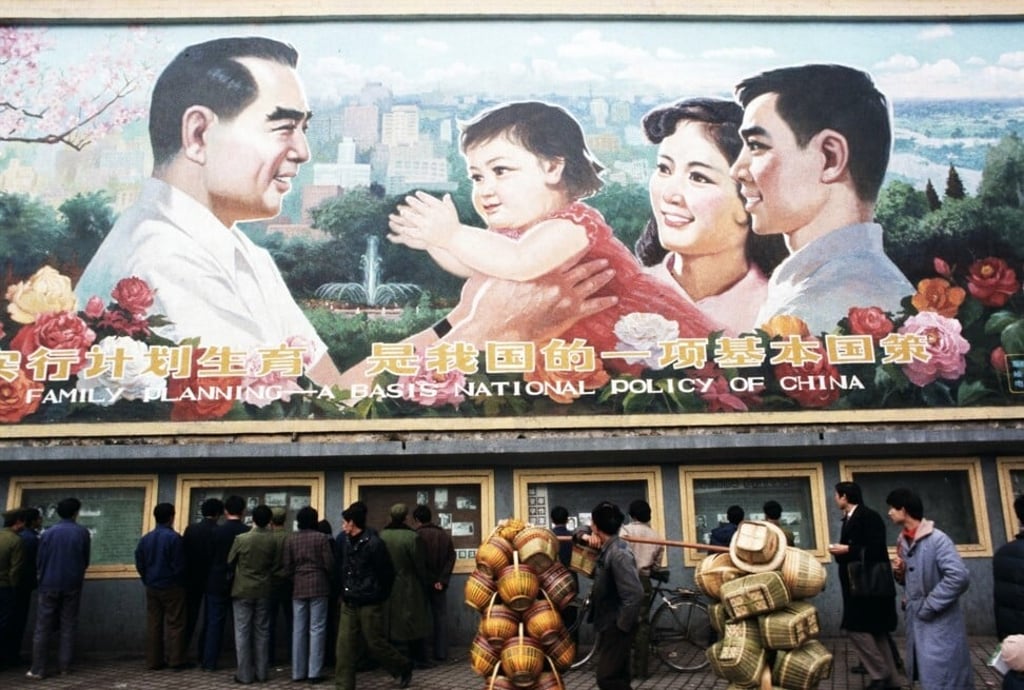 Pedestrians and a man carrying baskets pass by a huge billboard extolling the virtues of China's ‘One Child Family’ policy in 1985. Photo: Getty