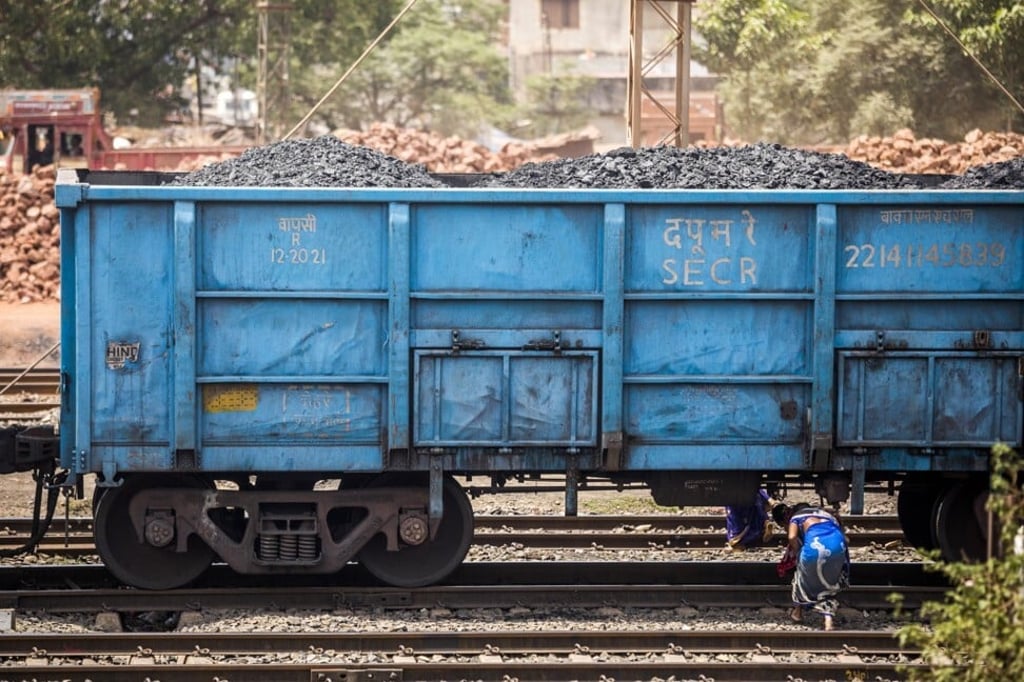 People walk under a freight wagon laden with coal in Jharkhand, India. File photo: Bloomberg