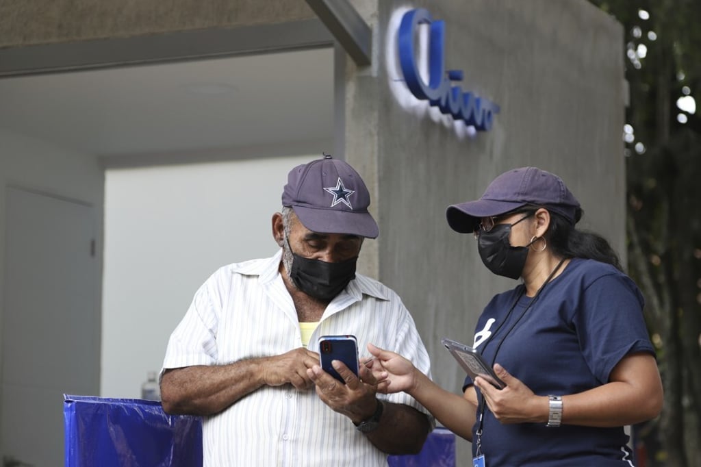 A promoter helps a man on the use and activation of his digital Chivo Wallet in Santa Tecla, El Salvador. Photo: AP