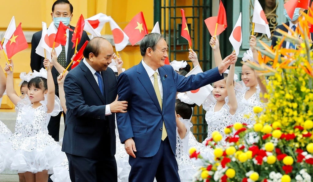 Japanese Prime Minister Yoshihide Suga (right) and his then Vietnamese counterpart Nguyen Xuan Phuc wave to children during a welcome ceremony at the Presidential Palace in Hanoi on October 19, 2020. Photo: Reuters