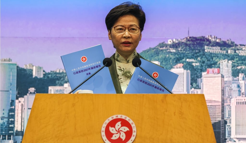 Carrie Lam holds up copies of her policy address during her weekly media briefing. Photo: Nora Tam