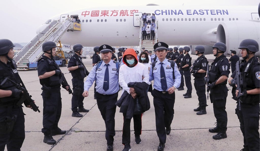 Police escort people accused of a telephone fraud scheme that were extradited from Spain in 2019. Photo: AP