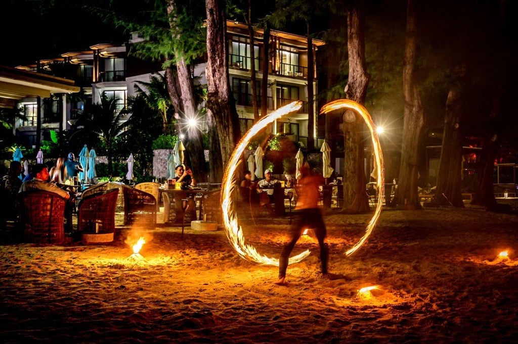 Tourists enjoy a fire show at a beachfront hotel in Phuket. Photo: AFP Tourists enjoy a fire show at a beachfront hotel in Phuket. Photo: AFP