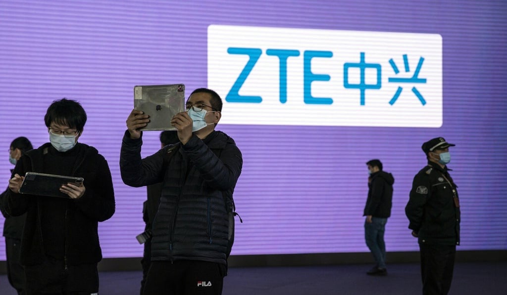 Attendees use tablets in front of signage for ZTE at the MWC Shanghai exhibition in February. Photo: Bloomberg