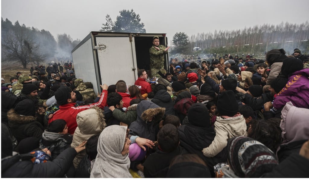 Migrants wait for humanitarian aid from the Belarus military. Photo: EPA