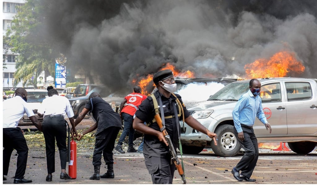 People extinguish a fire on cars caused by a bomb explosion in Kampala, Uganda. Photo: AFP People extinguish a fire on cars caused by a bomb explosion in Kampala, Uganda. Photo: AFP