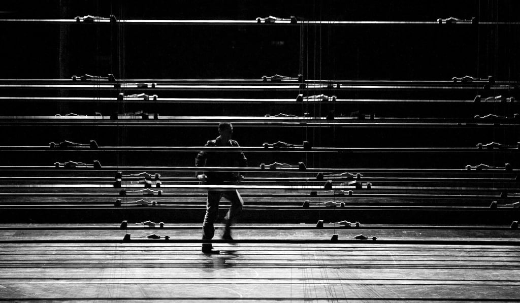 A performer navigates his way past onstage obstacles formed by slowly revolving lines of light rigs and gantries in the 2009 Athens production of ‘NOWHERE’. Photo: Marilena Stafylidou