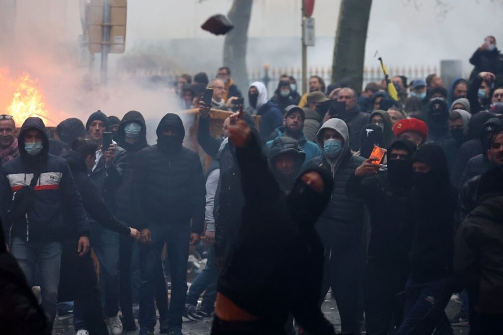 A protester throws stones towards riot police as clashes erupt during a demonstration against Covid-19 measures in Brussels, Belgium on Sunday. Photo: AFP A protester throws stones towards riot police as clashes erupt during a demonstration against Covid-19 measures in Brussels, Belgium on Sunday. Photo: AFP