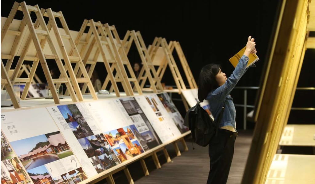 A visitor takes a photo at the 10 x 100 architecture exhibition at PMQ in Central. Hong Kong does have a fair number of privately owned art galleries, in addition to three art clusters for young artists and underfunded art groups, but they are scattered in different districts and are relatively small. Photo: Xiaomei Chen