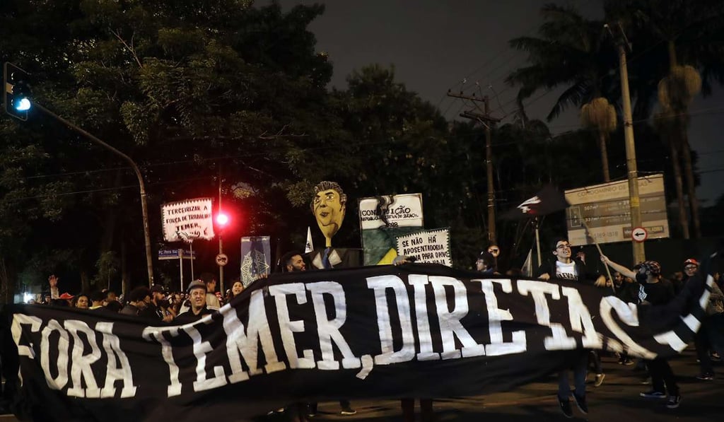 Demonstrators hold a banner that reads: ‘Get out Temer, elections now’, outside the residence of Brazil's President Michel Temer during a general strike in Sao Paulo, Brazil. Photo: AP