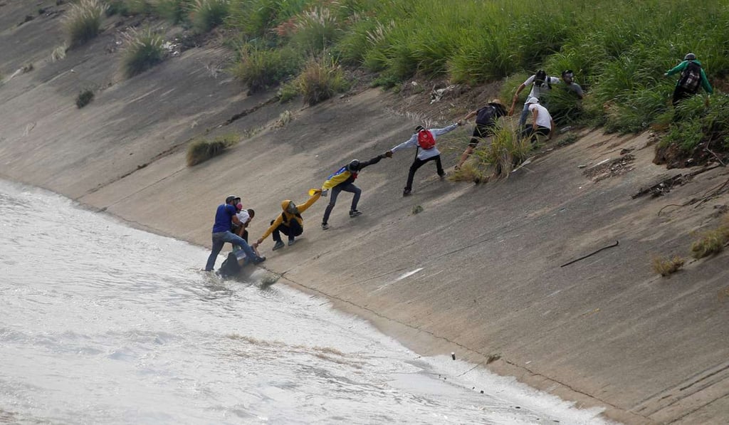 Protesters rescue a fellow protester who fell into the river during a rally against Venezuela's President Nicolas Maduro in Caracas on Monday. Photo: Reuters