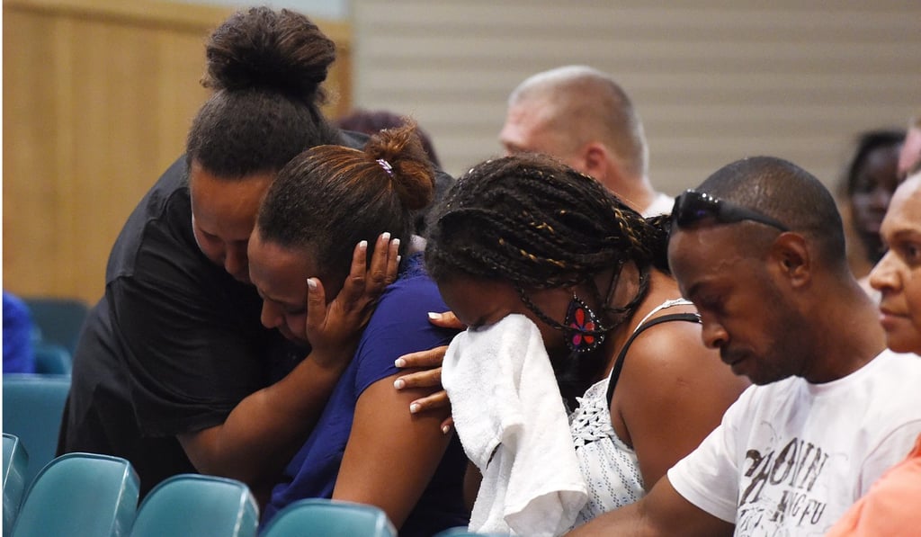 The father (second left) of three children who were among the eight children murdered by their mother, attends a memorial service in Cairns. Photo: EPA