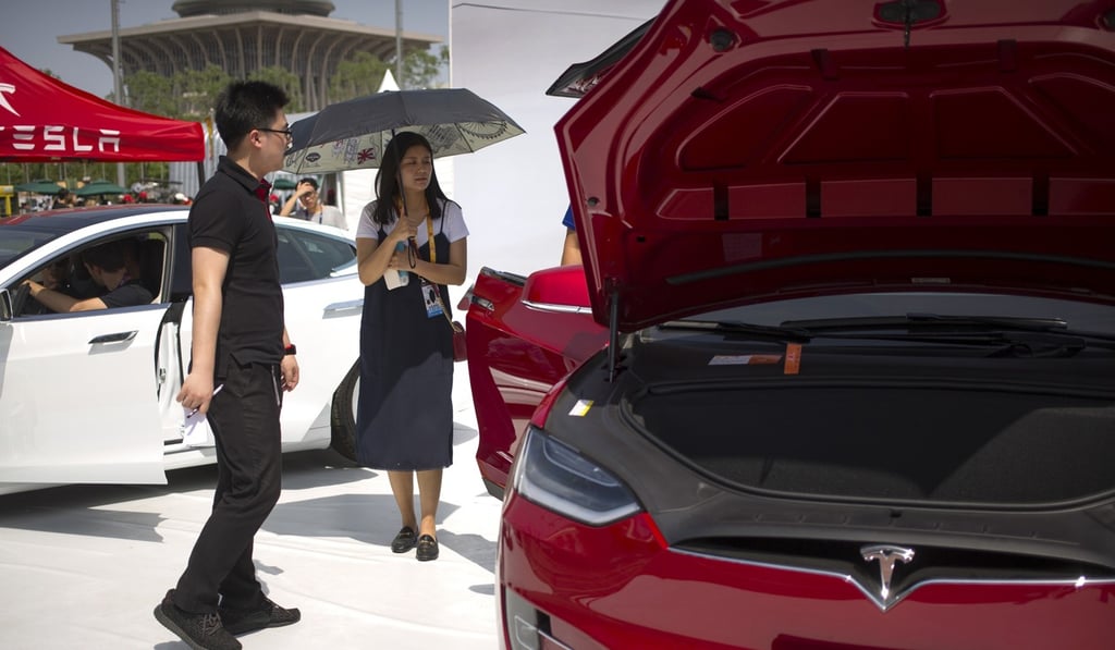 A visitor holds an umbrella as she looks at a Tesla Model X car on display at the G Festival, part of the Global Mobile Internet Conference (GMIC) in Beijing, late last month. Photo: AP