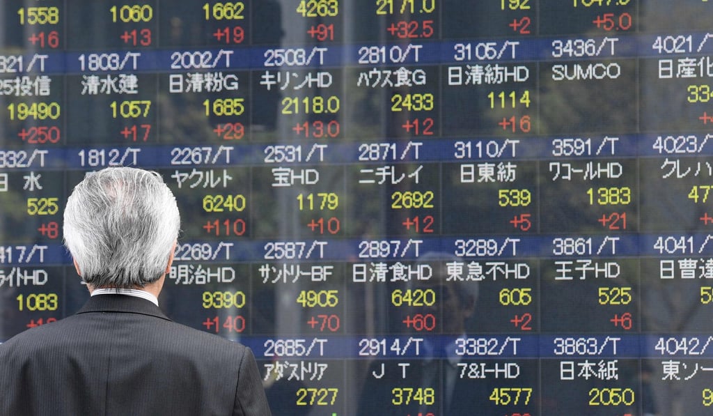 A businessman looks at an electronic share indicator at a securities company in Tokyo. Asian stocks are tipped to finish lower this treading week with investor looking forward to the US jobs report due out later on Friday. Photo: AFP