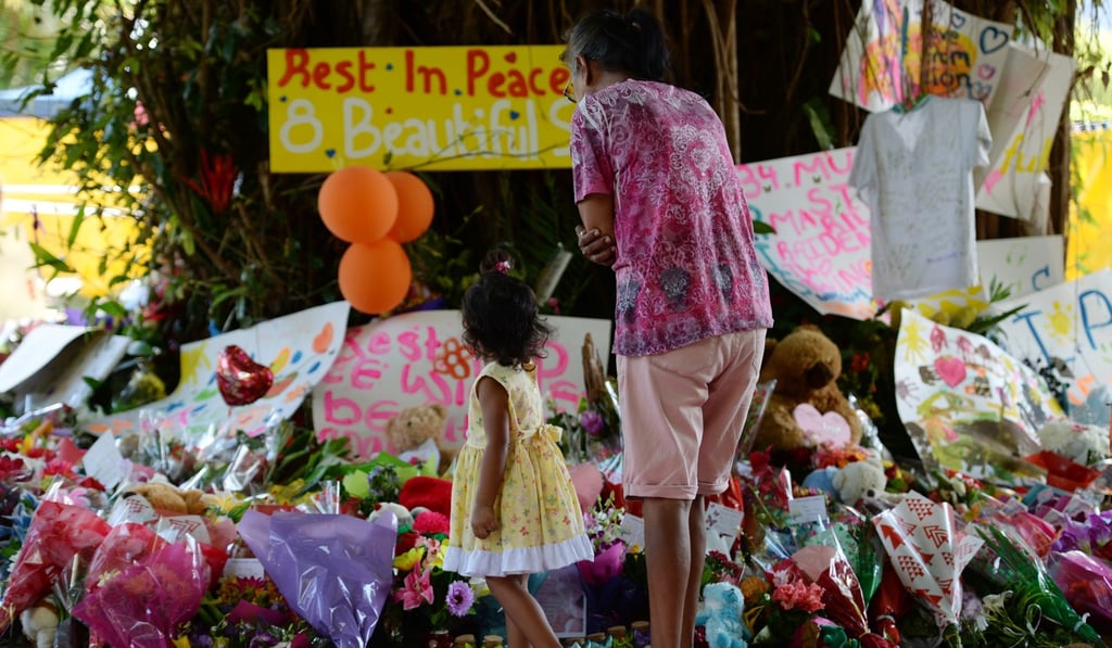 Mourners at the scene where eight children ranging from babies to teenagers were found dead in a house in the northern Australian city of Cairns. Photo: AFP