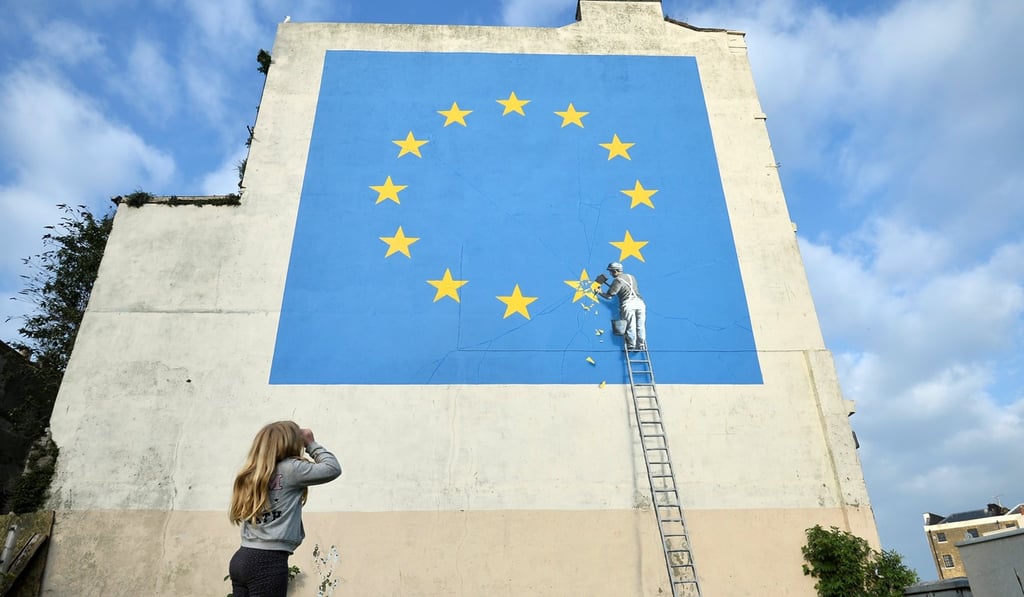 A girl looks at artwork attributed to street artist Banksy, depicting a workman chipping away at one of the 12 stars on the European Union, seen on a wall in the ferry port of Dover, Britain, on Sunday. Photo: Reuters