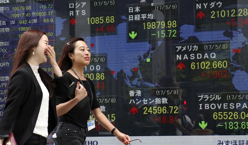Women walk past an electronic stock indicator of a securities firm in Tokyo on Tuesday. Photo: AP