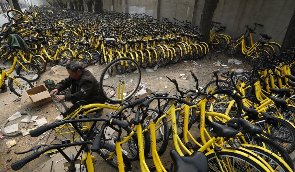 An employee fixes a bicycle's tyre at a repair station for the bike-sharing company Ofo in Beijing. Photo: AP