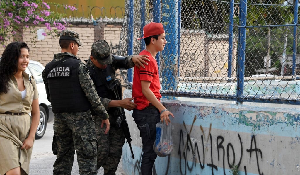 Military Police soldiers frisk a young man in the MS-13-controlled El Bosque neighbourhood in Tegucigalpa. The territorial fight between rival gangs has forced hundreds of people to flee. Photo: AFP Military Police soldiers frisk a young man in the MS-13-controlled El Bosque neighbourhood in Tegucigalpa. The territorial fight between rival gangs has forced hundreds of people to flee. Photo: AFP