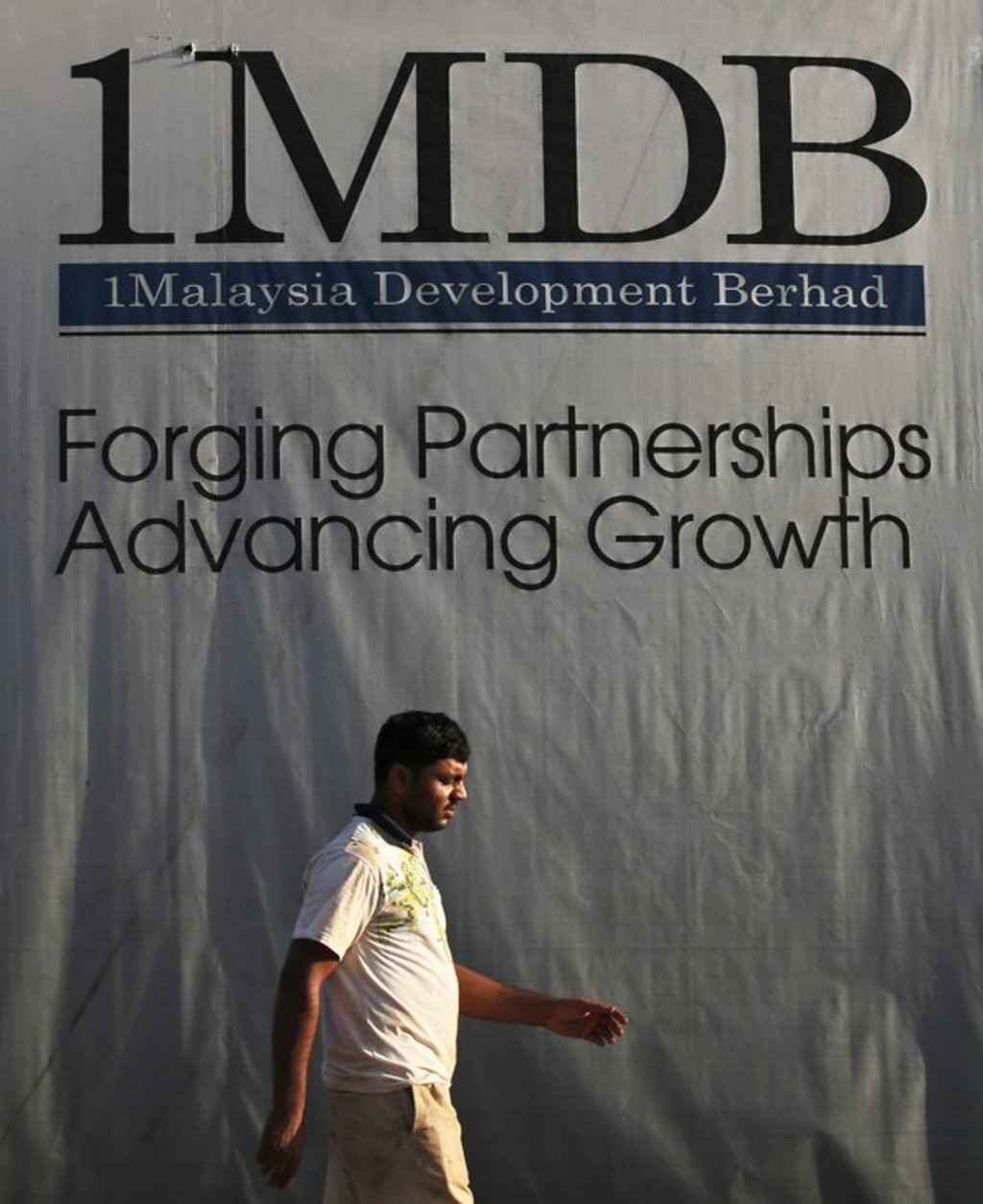 A man walks past a billboard of the troubled Malaysian state fund 1MDB in Kuala Lumpur, Malaysia. Photo: EPA