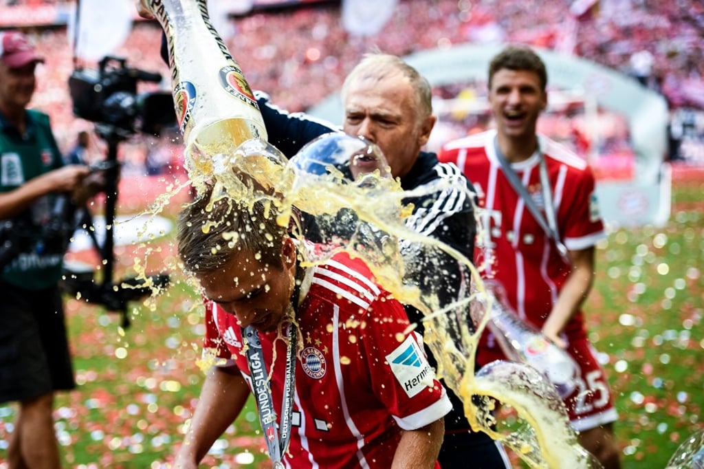 Bayern Munich’s Philipp Lahm receives a beer shower from assistant coach Hermann Gerland. Photo: EPA