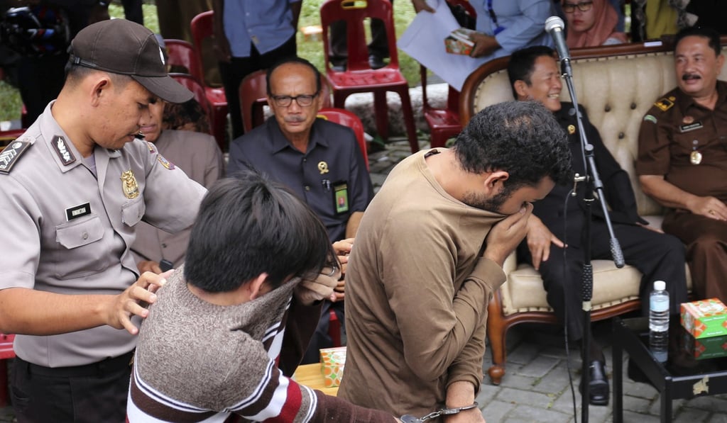 A police officer escorts two men convicted of gay sex to be publicly caned at a mosque in Banda Aceh, Aceh province Indonesia. Photo: AP