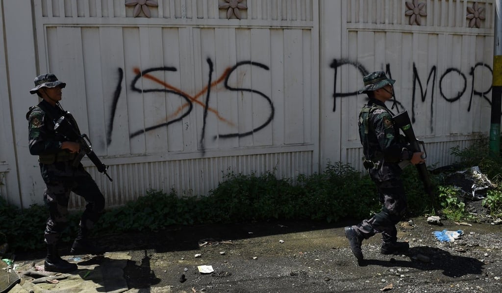 Philippine soldiers walk past Islamic State (IS) group graffiti in Marawi. Photo: AFP