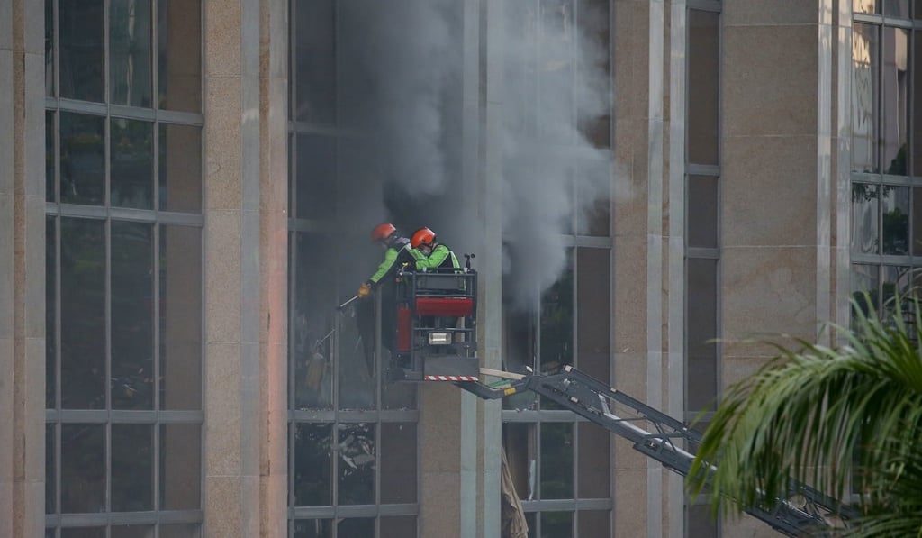 Firemen break windows to allow the smoke to escape from the Resorts World Manila complex. Photo: AP