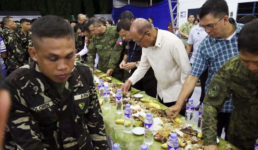 Philippine President Rodrigo Duterte takes part in a Filipino military mess hall meal known as a boodle fight. Photo: EPA