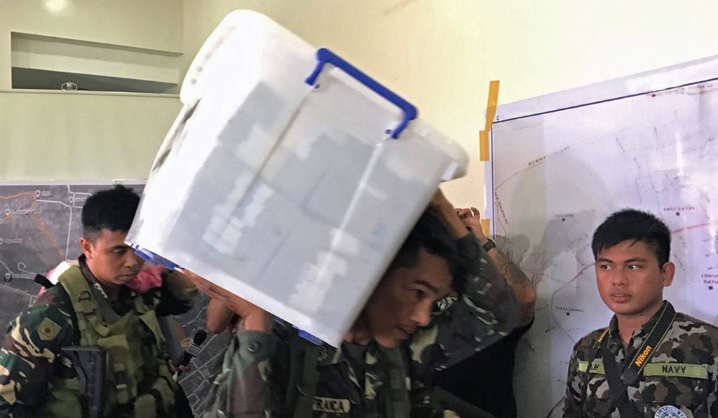 A government soldier carries a box containing cash seized from a vault in a house previously controlled by militants. Photo: Reuters