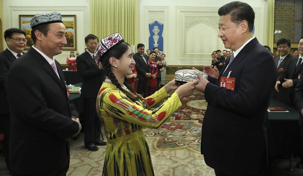 Xi Jinping receives a traditional Uygur hat, a gift symbolising the highest respect and best wishes from people of all ethnic groups in Xinjiang, as he joins a panel discussion with deputies to the 12th National People's Congress from the Uygur autonomous Region, in Beijing on March 10. Photo: Xinhua
