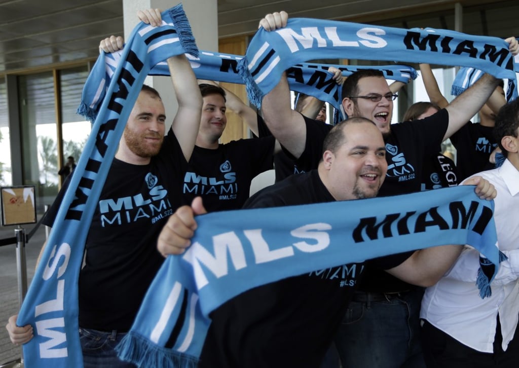 Supporters hold up scarves before a news conference where Beckham announced he will exercise his option to purchase a Major League Soccer expansion team in Miami. Photo: AP Supporters hold up scarves before a news conference where Beckham announced he will exercise his option to purchase a Major League Soccer expansion team in Miami. Photo: AP