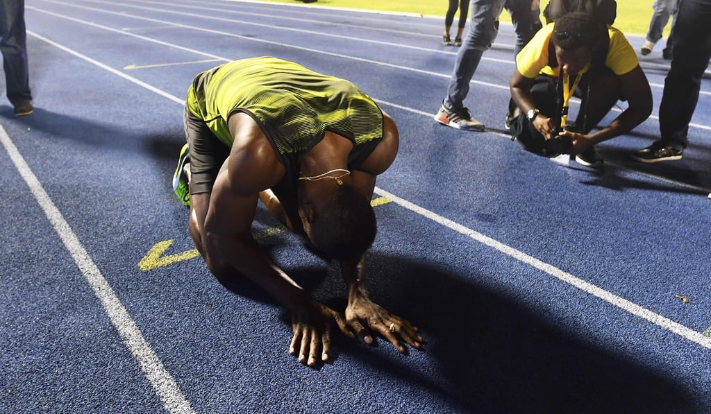 Usain Bolt kneels to kiss the track at the national stadium in Kingston, Jamaica. Photo: AFP
