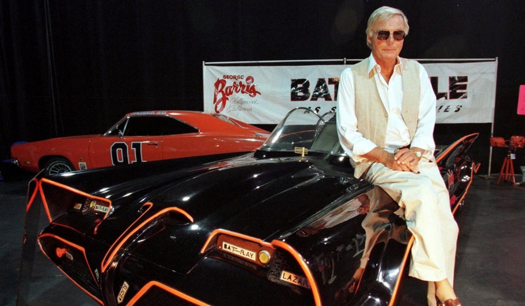 Adam West poses atop the original Batmobile used in the hit series. Photo: Reuters
