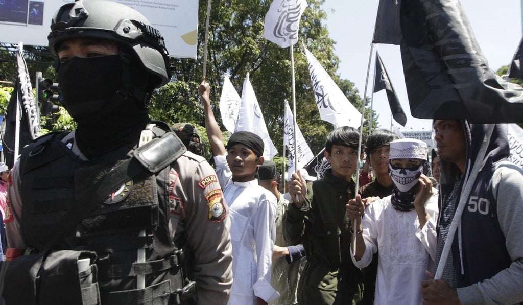 Police next to members of the radical Hizb ut-Tahrir Indonesia (HTI) during a rally in Makasar. Photo: AFP Police next to members of the radical Hizb ut-Tahrir Indonesia (HTI) during a rally in Makasar. Photo: AFP