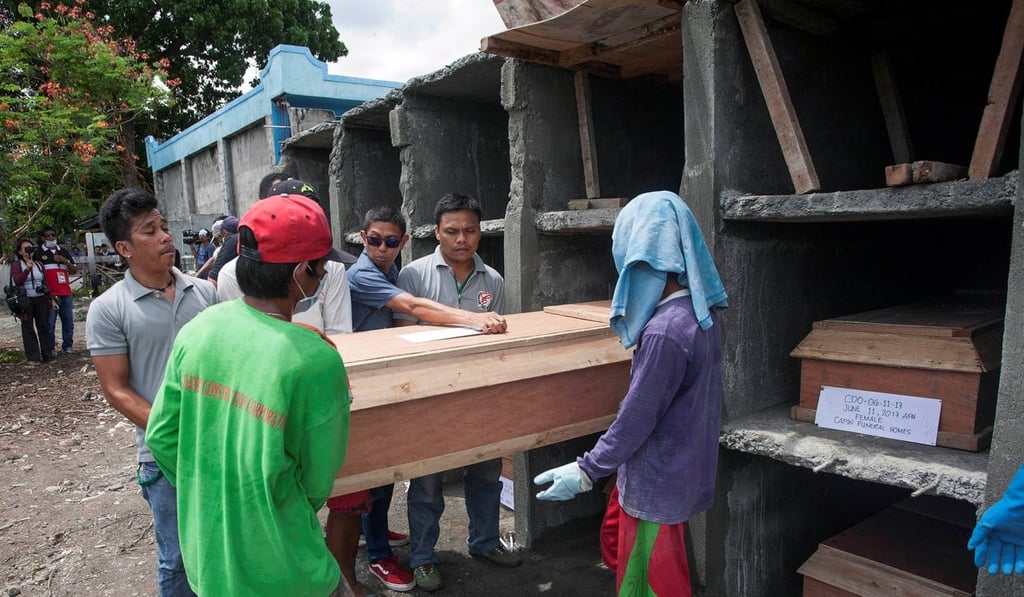 Funeral workers lift a coffin containing one of the civilians who was killed in a firefight between government troops and insurgents. Photo: Reuters