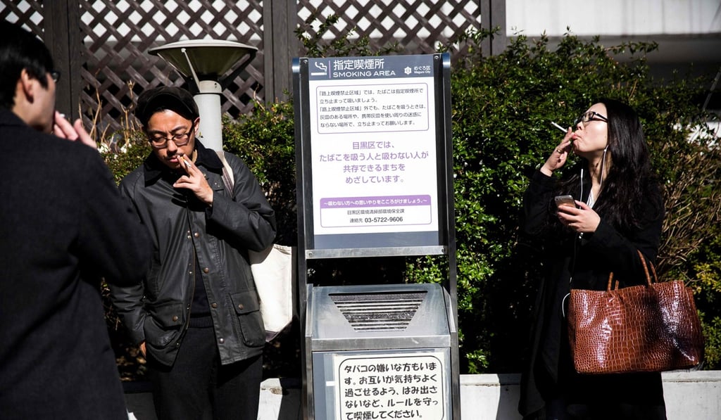 People smoke cigarettes at a designated outdoor smoking area in the Naka-Meguro neighbourhood of Tokyo. Photo: AFP