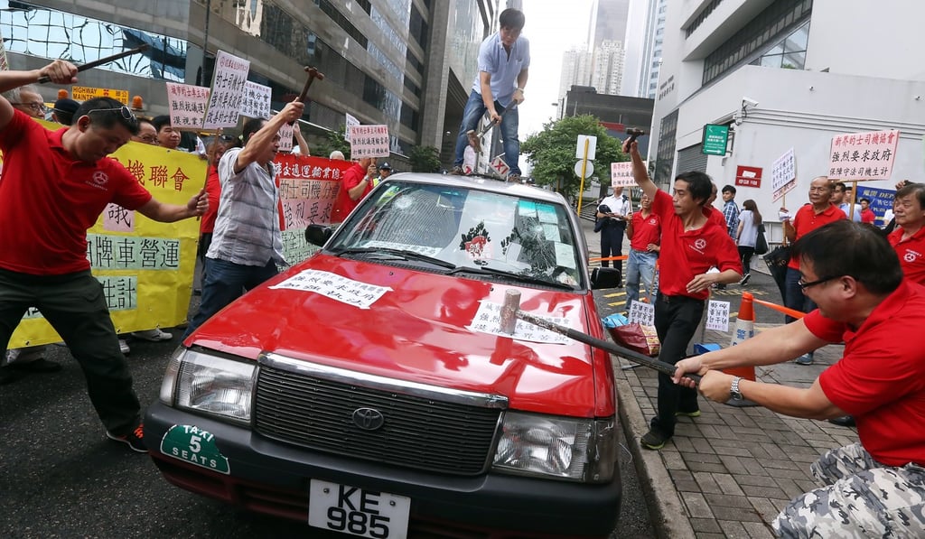 Drivers smash a taxi to call on the government to ban ride-sharing services, outside Wan Chai Towers on July 24, 2015. Photo: Dickson Lee