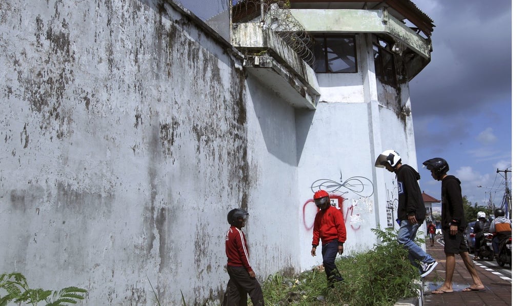 Residents observe a hole in the ground through which four foreign inmates have escaped from Kerobokan prison. Photo: AP