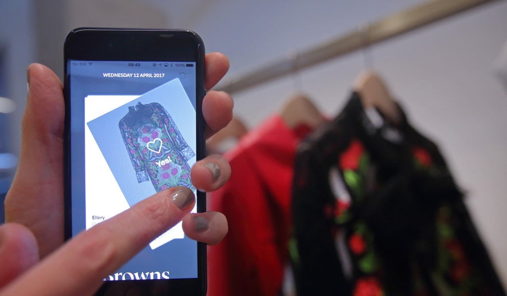 An employee demonstrates the use of a smartphone app linked to fashion products at the launch of the Farfetch U.K. Ltd. in London on April 12. Photo: Bloomberg