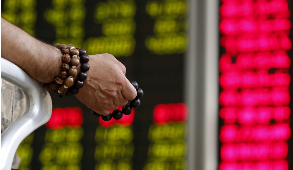 An investor holds prayer beads as he watches a board showing stock prices at a brokerage office in Beijing. The Shenzhen-Hong Kong Stock Connect allows international investors to trade the shares of smaller, more entrepreneurial companies, whose growth is a critical component of China’s economic reform. Photo: Reuters
