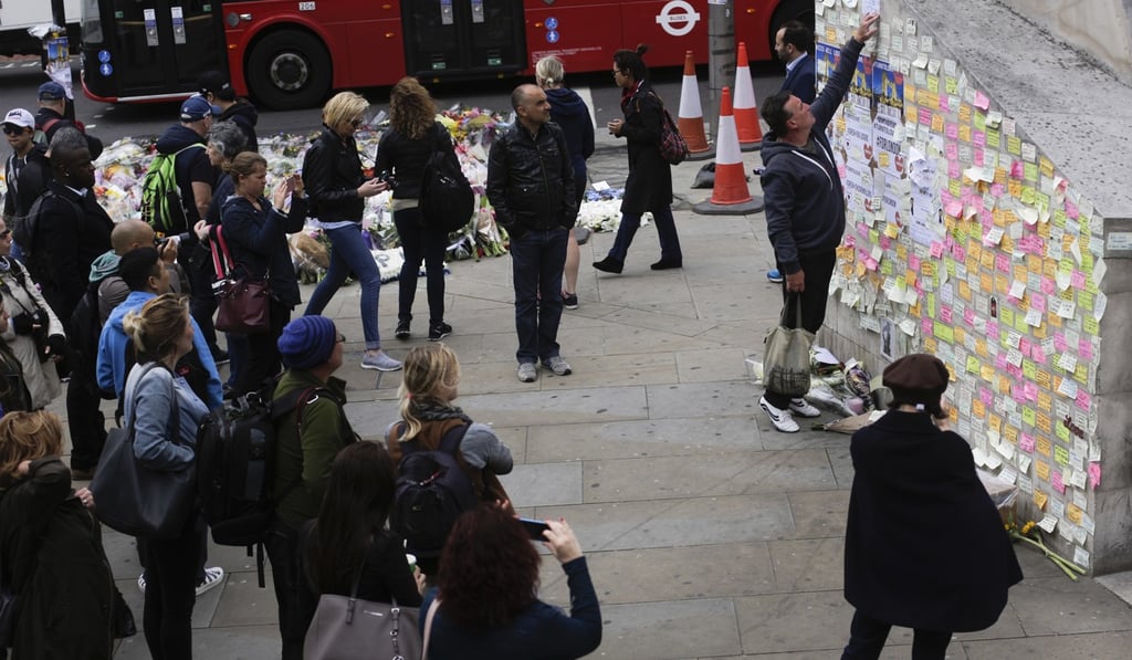 A man fixes a paper between other messages against an attack on a wall near the London Bridge in London. Social media companies are banding together to help stamp out extremist content on their sites. Photo: AP