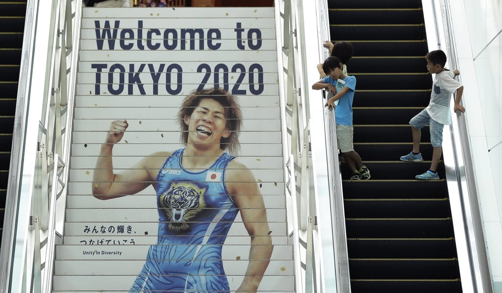 Children take an escalator while the Tokyo 2020 Olympic Games Preparation emblem is displayed on stairs at the International Terminal of Haneda Airport. Photo: EPA