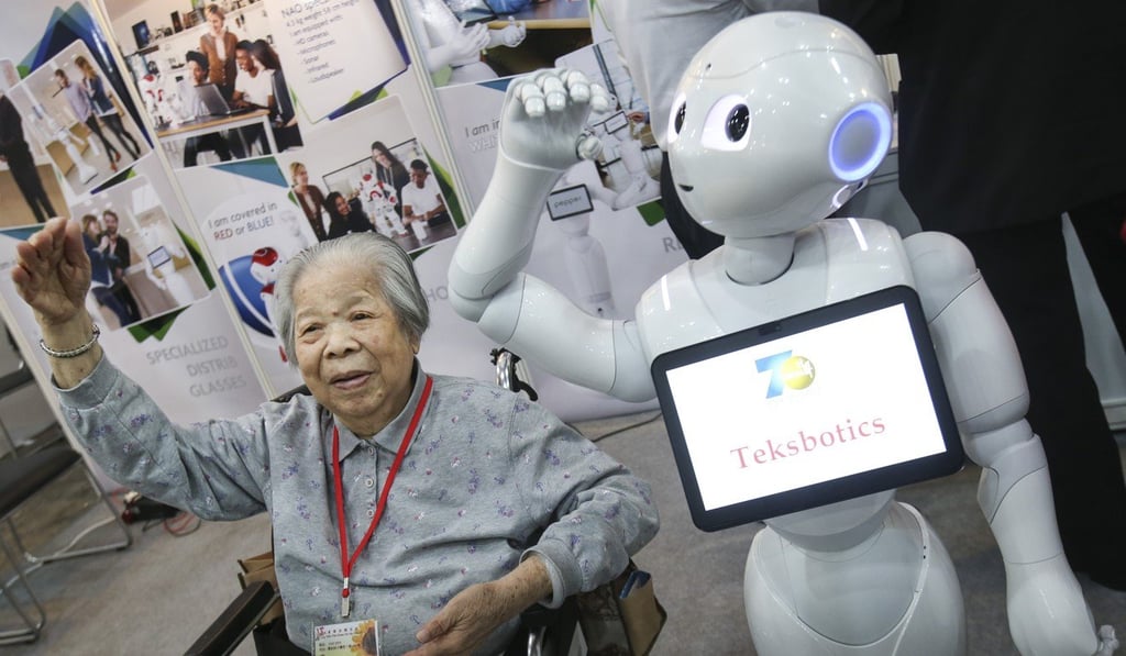 Fong Ying, 85, follows the dance steps of a robot at the Gerontech and Innovation Expo in Hong Kong in June. Artificial intelligence empowers people but it will never replace them, according to the author. Photo: David Wong
